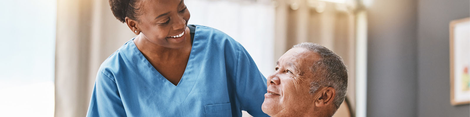 A nursing assistant looking down smiling at a senior memory care resident